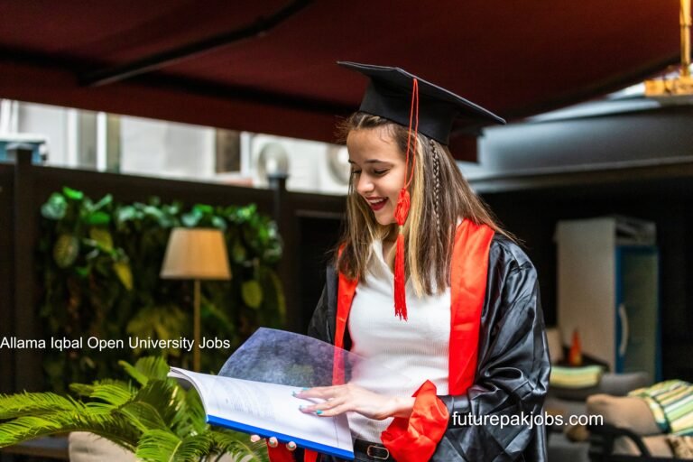 young student wearing graduation cape looking her notebook 1 1